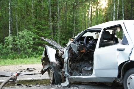 This is a picture of a small white car that is all smashed up, probably from a car accident.